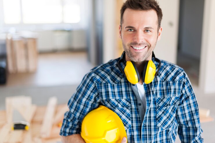 Smiling skilled worker holding a safety helmet